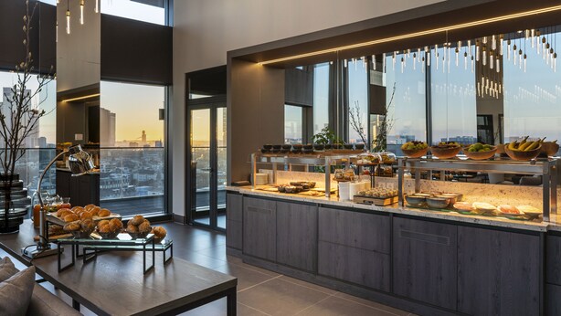 Een moderne keuken met een ontbijtbalk, grote ramen en uitzicht over de stad.