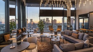 Een moderne lounge met zitplaatsen, tafels en uitzicht over de stad.