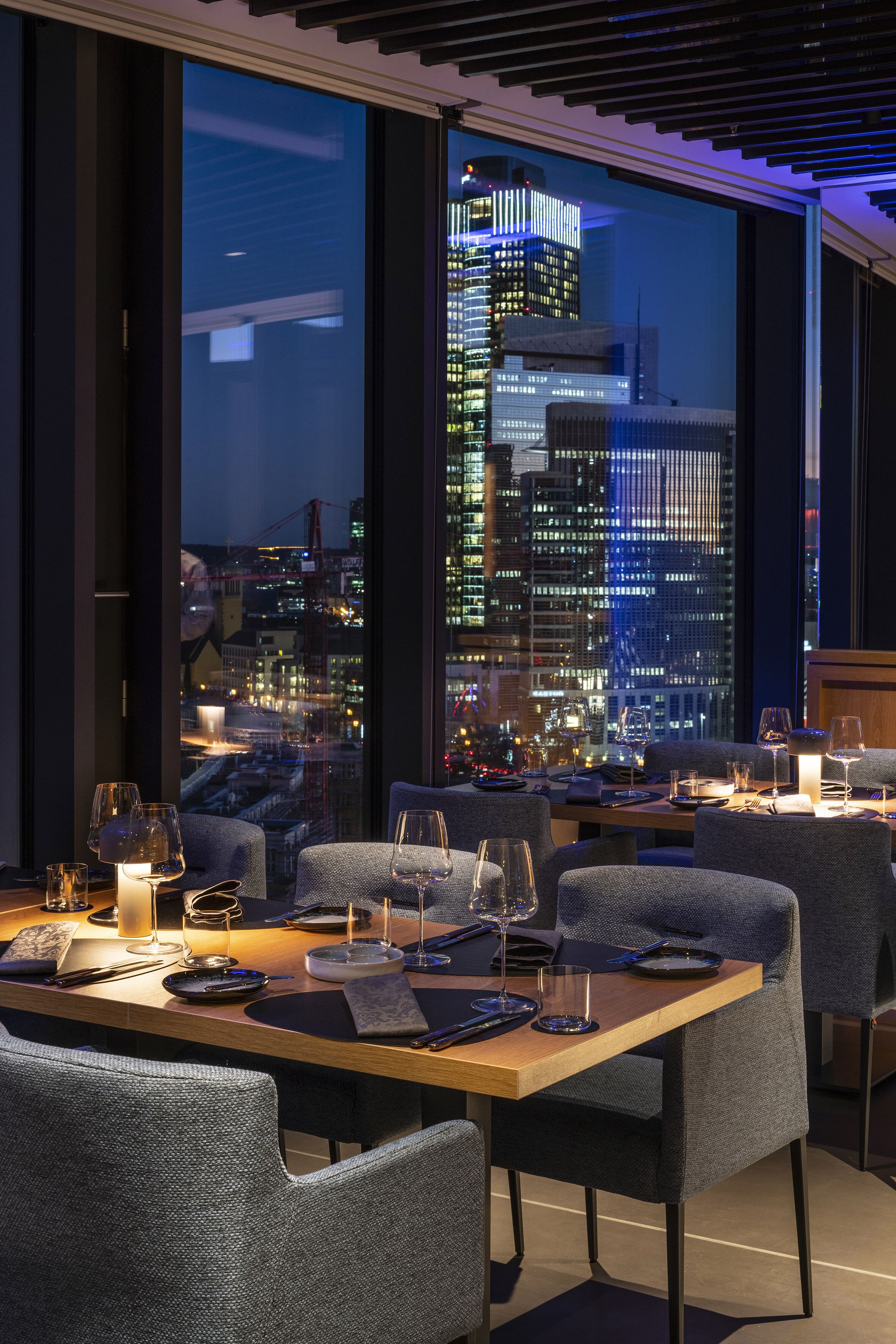Un restaurant amb vista a la ciutat, mobiliari modern i una zona de menjador ben il·luminada.