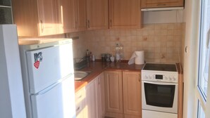 Una cocina con armarios de madera, un refrigerador blanco, una estufa y un lavamanos.