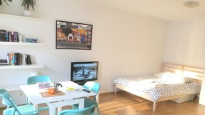 Una habitación con una cama, un escritorio con una silla, un televisor y una estantería.