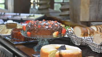 A buffet with various food items including a chocolate cake topped with strawberries, bread, and a fruit slice.