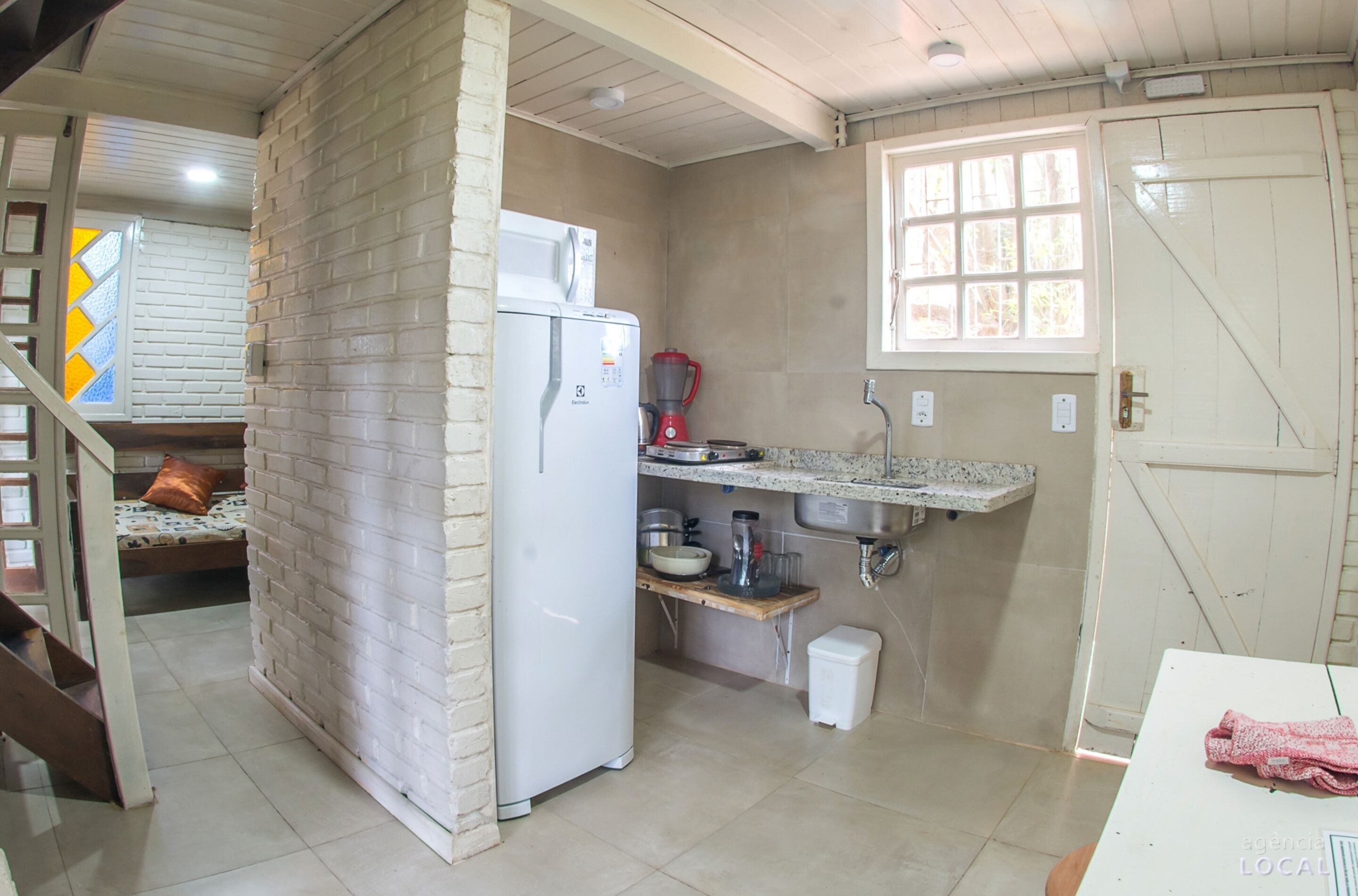 A compact kitchen with a refrigerator, a coffee maker, and a sink.