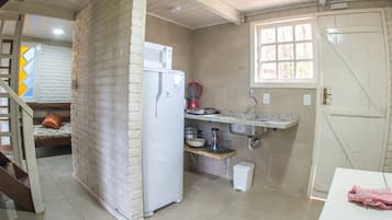 A compact kitchen with a refrigerator, a coffee maker, and a sink.
