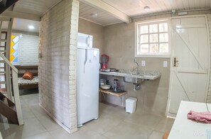 Een kleine keuken met een koelkast, een koffiezetapparaat en een spoelbak.