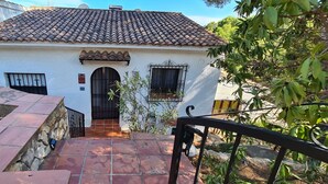 A white building with a tiled roof, a black gate, and a small window with a metal grille. - Detached house with terrace in the middle of a pine forest with sea view (Altea la vella)