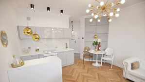 A modern kitchen with white cabinetry, a wooden herringbone floor, and a dining area with a white table and chairs.