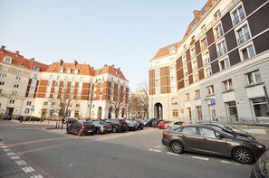 A street view with parked cars and multi-story buildings with balconies. - Apartament Superior-Aleja Wyzwolenia 3-5 (Warsaw)