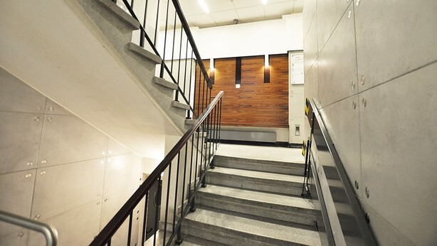 A staircase with a metal railing, a wooden panel wall, and tiled walls.