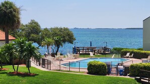 Une piscine avec des chaises longues, une terrasse en bois et une vue sur la mer.