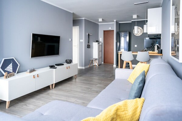 A modern living room with a grey sofa, a flat-screen TV, and a white entertainment unit. - Apartament - ul. Marszałkowska 111A (Warsaw)