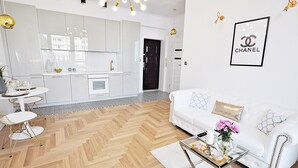 A modern living room with a white sofa, a glass coffee table, and a herringbone wood floor. - Apartamenty - ul. Marszałkowska 85 (Warsaw)
