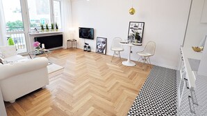 A modern living room with a white sofa, a TV, and a fireplace. - Apartamenty - ul. Marszałkowska 85 (Warsaw)