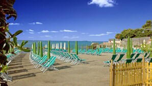 A beach with rows of green lounge chairs and umbrellas, a wooden fence, and a clear blue sky. - Residenza Venus - Venus Grazioso bilocale -50 mt dal mare (Castiglioncello)