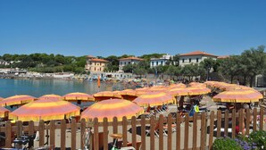 A beach with rows of sun umbrellas and beach chairs, a wooden fence, and buildings in the background. - Residenza Venus - Venus Grazioso bilocale -50 mt dal mare (Castiglioncello)