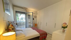 Una camera da letto con un letto, una lampada da comodino, un armadio e un tavolino con un vaso di fiori.