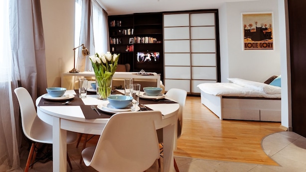 A modern living room with a dining area, a bookshelf, a TV, and a sofa. - Apartament balkon-Aleje Jerozolimskie 29 (Warsaw)