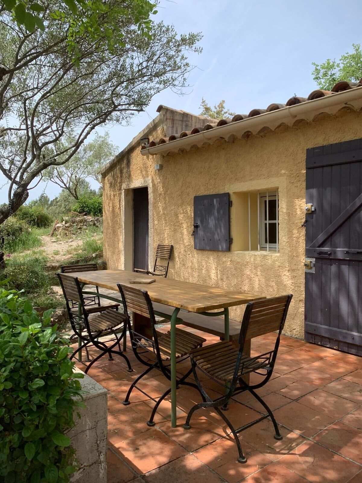 Un espace de restauration extérieur de style rustique, avec une table et des chaises, une porte et une fenêtre.