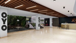 Un interior moderno con mostrador de recepción, zona de estar y una escalera.