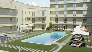 Un moderno edificio de apartamentos con piscina central, mobiliario exterior y un patio cubierto.