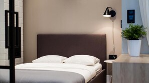 A neatly made bed with white linens, a dark headboard, and a bedside table with a potted plant. - Apartament-ul. Marszałkowska 58 (Warsaw)