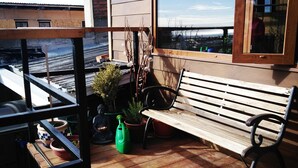 Una terraza de madera con un banco y plantas en macetas.
