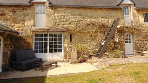 A stone building with a thatched roof patio, a wooden bench, and a ladder. - Penty Gwen in a listed 17th century Breton farmhouse for 4 people (Crozon)