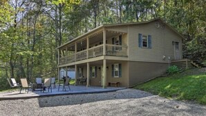 A two-story cabin with a balcony, outdoor seating, and a gravel driveway. - The Hideaway at Buck Ridge. Pet friendly. (Chesterhill)