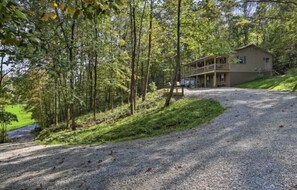 A two-story building with a balcony, surrounded by trees and a gravel driveway. - The Hideaway at Buck Ridge. Pet friendly. (Chesterhill)