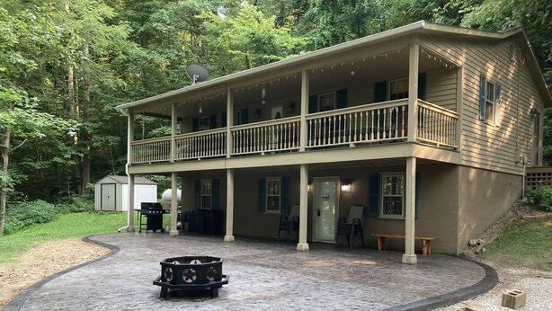 A two-story house with a covered patio area, a barbecue setup, and outdoor seating. - The Hideaway at Buck Ridge. Pet friendly. (Chesterhill)