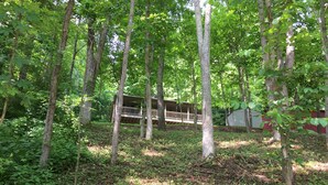 A forested area with a cabin featuring a balcony. - The Hideaway at Buck Ridge. Pet friendly. (Chesterhill)
