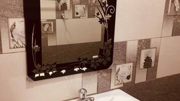 Une salle de bain avec un lavabo blanc, un miroir à cadre noir et des carreaux décoratifs.