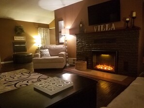 Een gezellige woonkamer met een open haard, een comfortabele fauteuil en een salontafel met een spel.