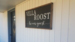 Et skilt på en hvid væg med teksten: Villa Roost, vær vores gæst.