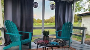 En veranda med to turkise Adirondack-stole, et lille rundt bord med en potteplante og en pyntende blomsteropsætning.