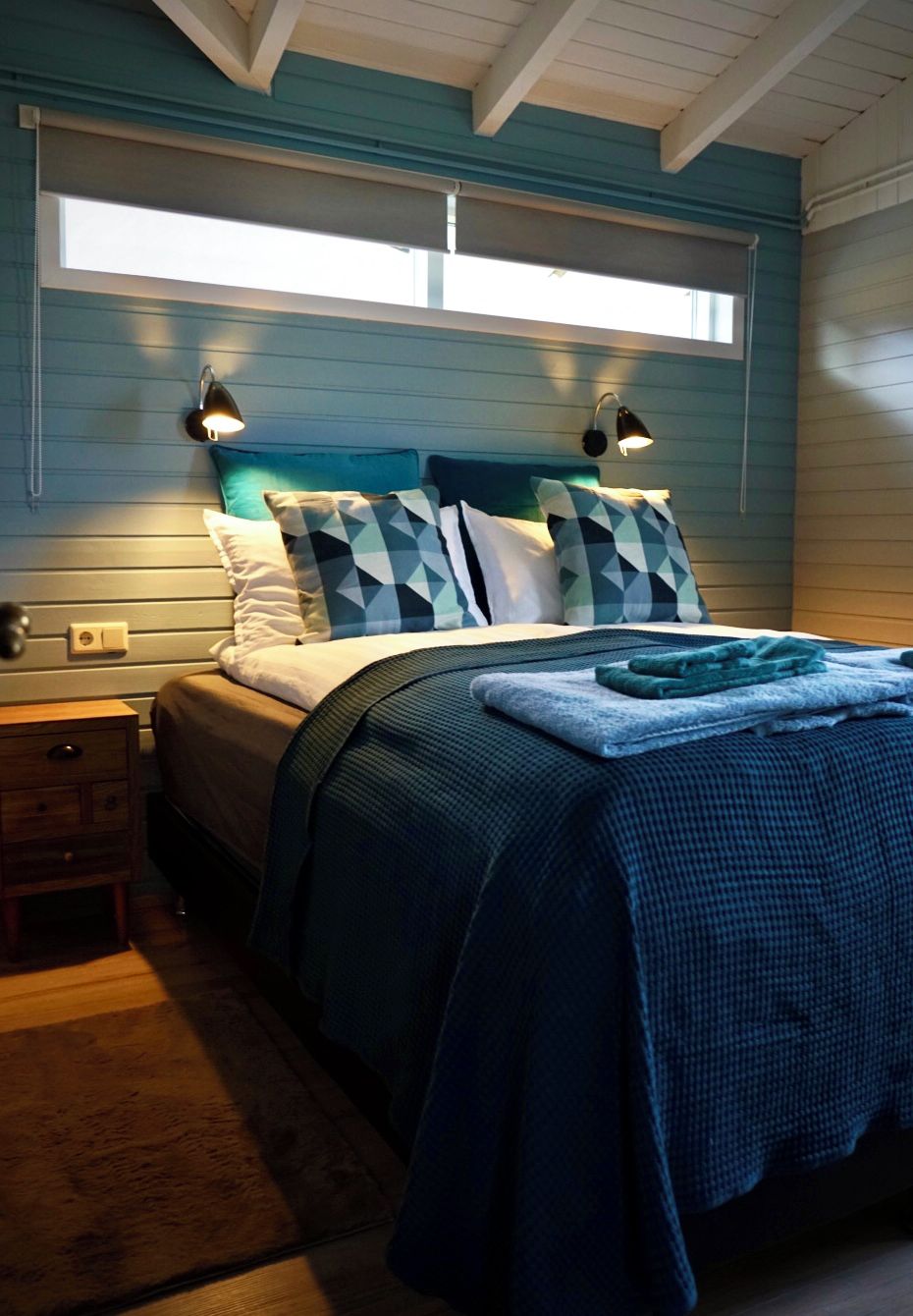 A bedroom with a bed, nightstands, a window, and a headboard.