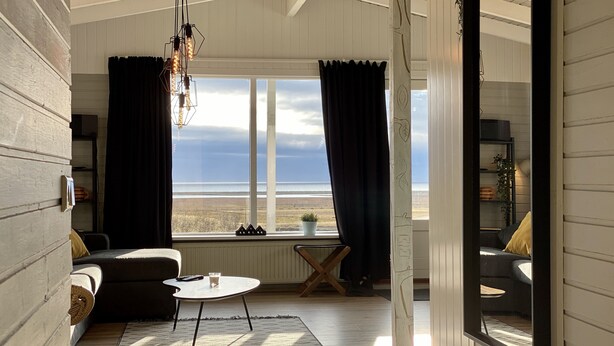 Una sala de estar acogedora con vista al mar, una mesa de centro redonda y una estantería.