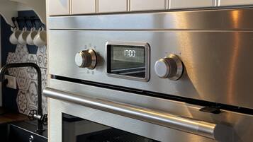 Un horno de acero inoxidable con pantalla digital y dos mandos giratorios.