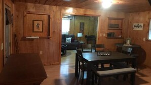 Un interior de madera con una mesa de comedor, sillas, un sofá y una pequeña zona de cocina.