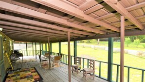 Un espacio al aire libre cubierto con suelo de madera, un tapete a cuadros y varias sillas y mesas de madera.