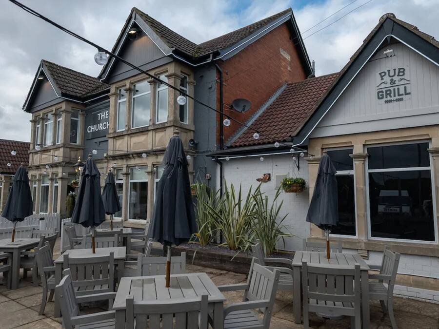 Un pub con mesas al aire libre y un letrero que dice 'PUB & GRILL'.