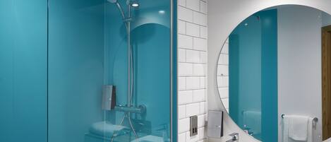 A modern bathroom with a glass-enclosed shower, a white sink, and a round mirror.