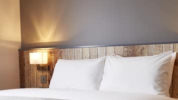 A neatly made bed with white linens and a wooden headboard.