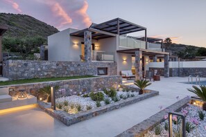 A modern house with a stone facade, outdoor seating, and a pool. - Yades Instyle Villas (Sitia)