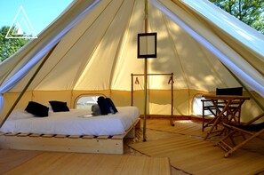 A tent with a bed, a small table, and a hanging light fixture. - Logd'ing Nature Camp Luberon (Saint-Michel-l'Observatoire)