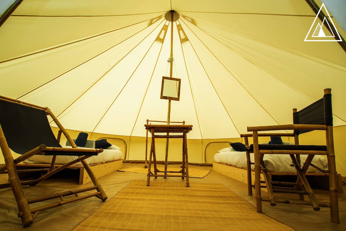 A tent with two beds, a table, and a chair.