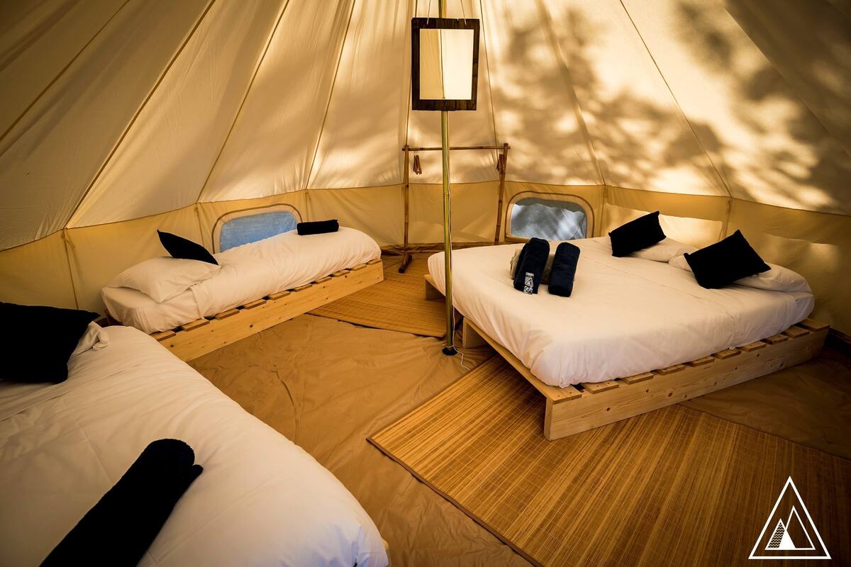 A tent with two beds, each with pillows and a small table.