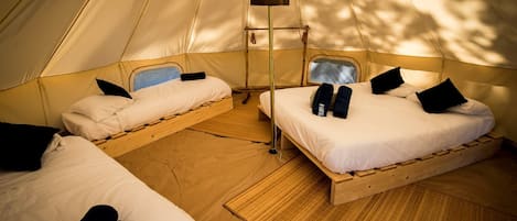 Una carpa con dos camas, cada una con almohadas y una mesita.