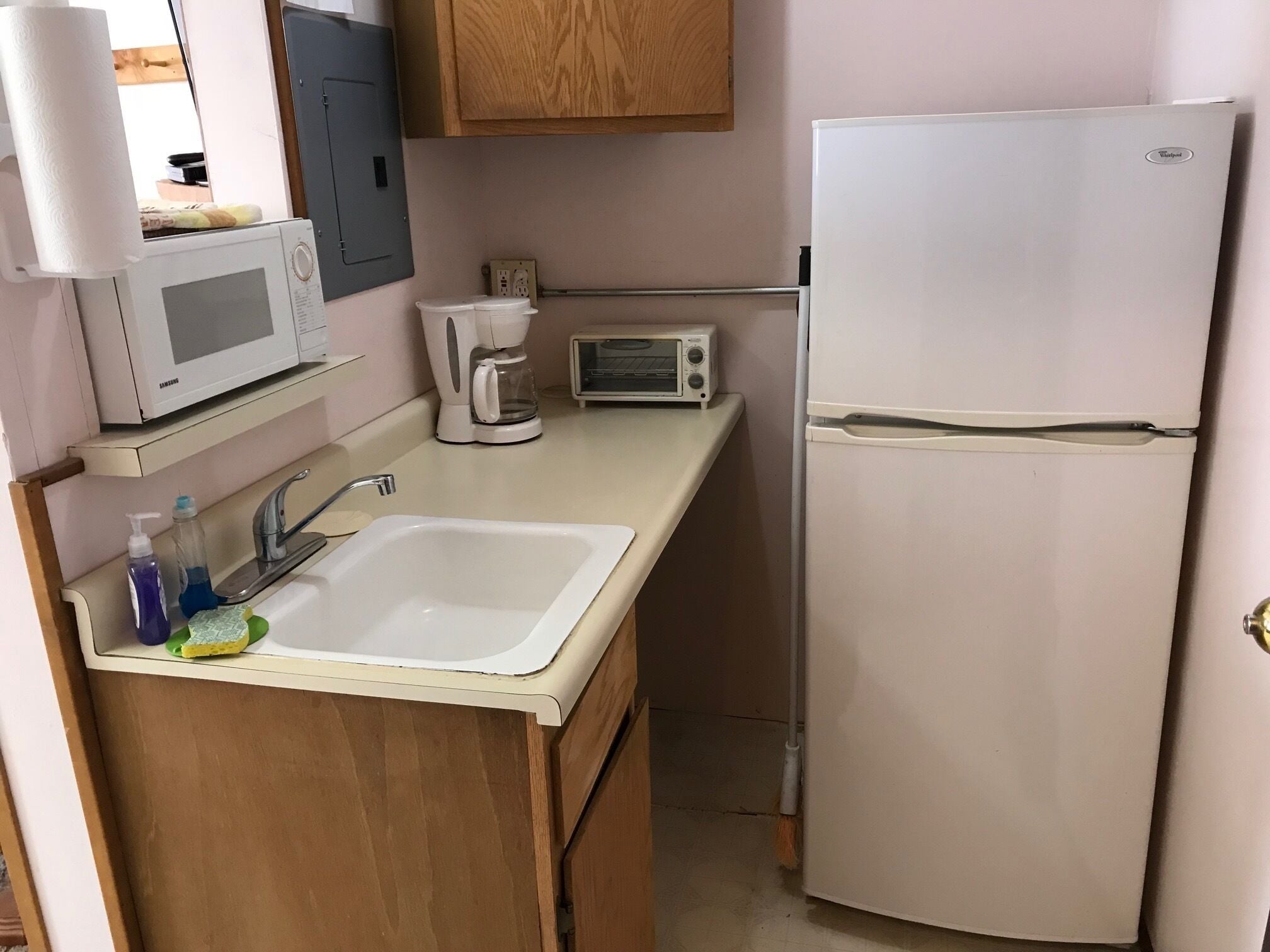 A compact kitchenette with a microwave, toaster, coffee maker, and a refrigerator.
