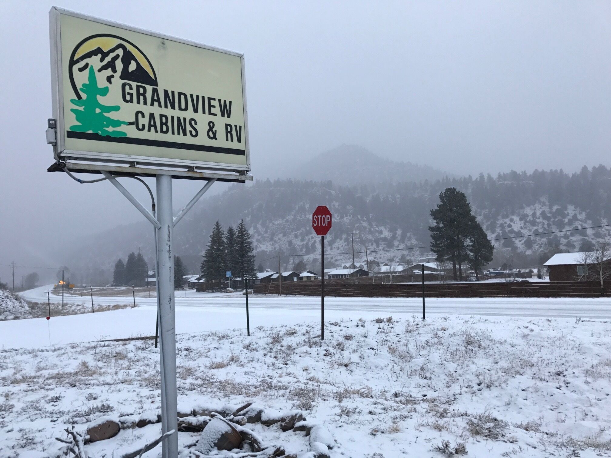 A sign for Grandview Cabins & RV in a snowy landscape with a stop sign nearby.